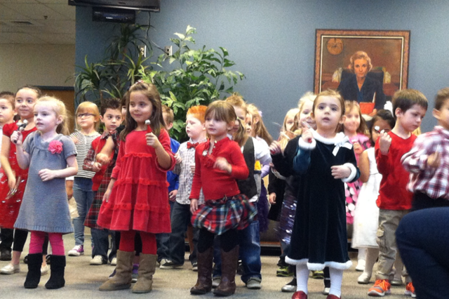Children preforming hoilday songs in office.