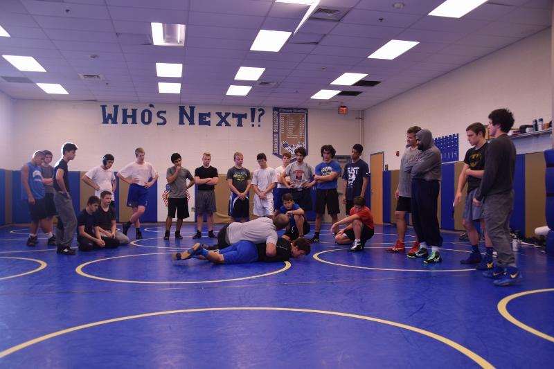 Coach John DeVito pins down varsity wrestler Aaron Mayer to demonstrate a move to the entire team during practice.