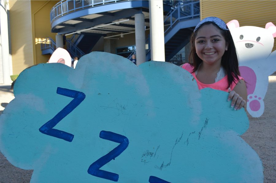 Mila Alarcon, sophomore, poses with a spirit week bulletin in her sleep attire to complement the spirit week theme.