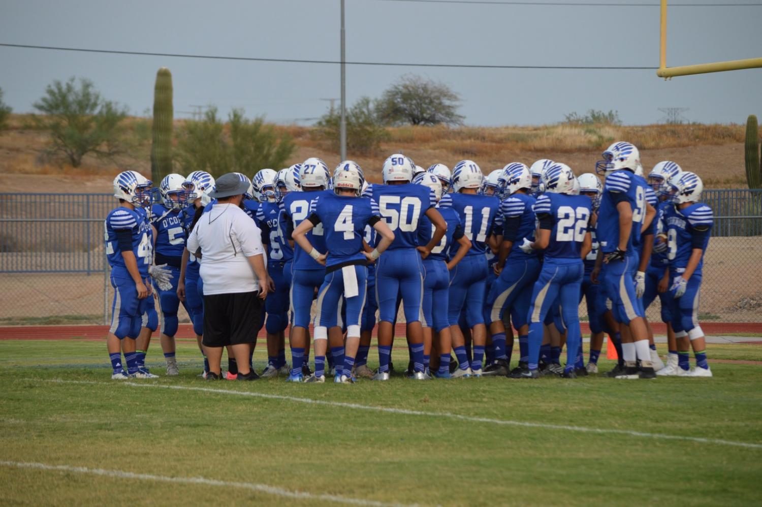 The JV football team huddle together to discuss their new game plan. 