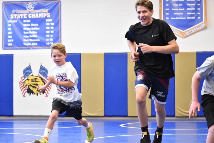 Jacob Correa, junior, runs with Max Bode, brother of wrestling club member Zach Bode, junior, during a club meeting.