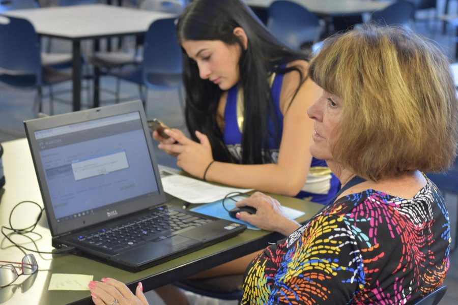 Ruby Miller, Rio Salado representative, helps a student register to a dual course in the OHS library.