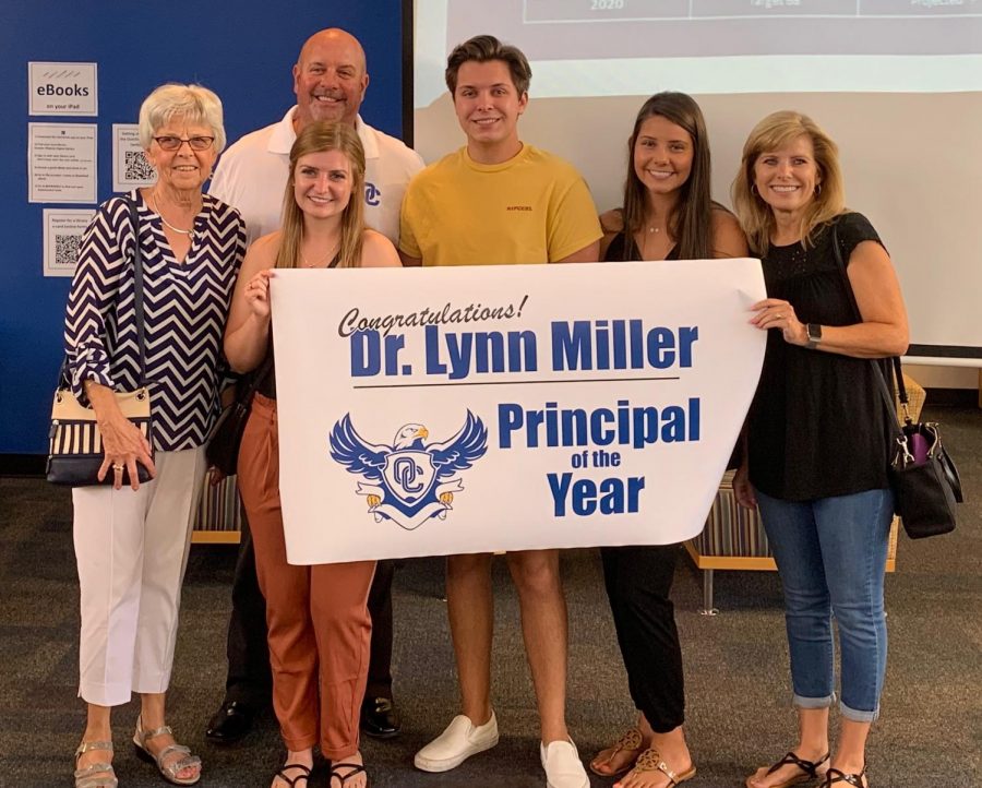 Dr. Lynn Miller standing beside his family as he receives Principal of the Year Award.