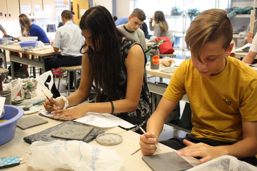 Tanner Valus, sophomore, and Akshara Taikella, senior, carefully etch out their designs on the clay tiles.