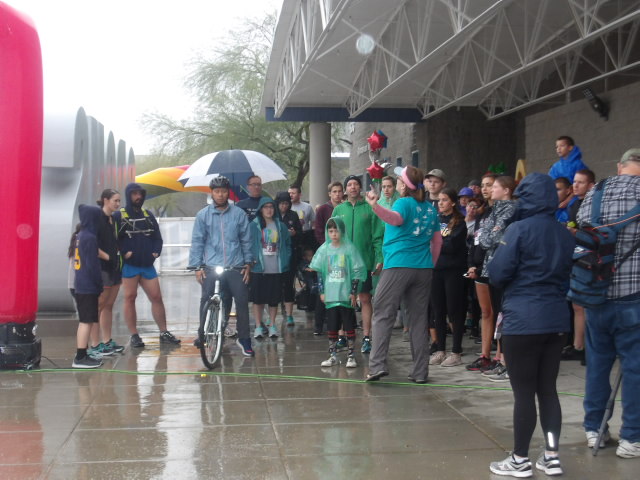 Racers stand at the start line, gearing up to begin their race in the rain.