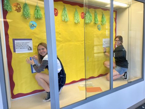 Alison Paulos, junior, and Brooklyn Smith, junior, set up the display case for Hispanic Heritage Month.