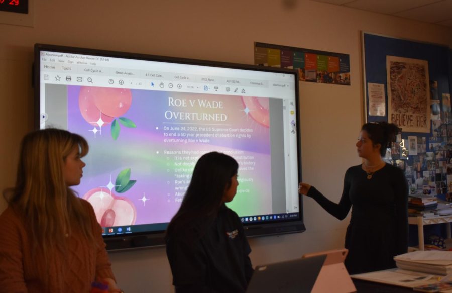Julia Martin (left), senior, Ananya Iyer (middle), senior, and Tala Shammas (right), junior, present a presentation on the overturn of Roe v. Wade and its effects on women.