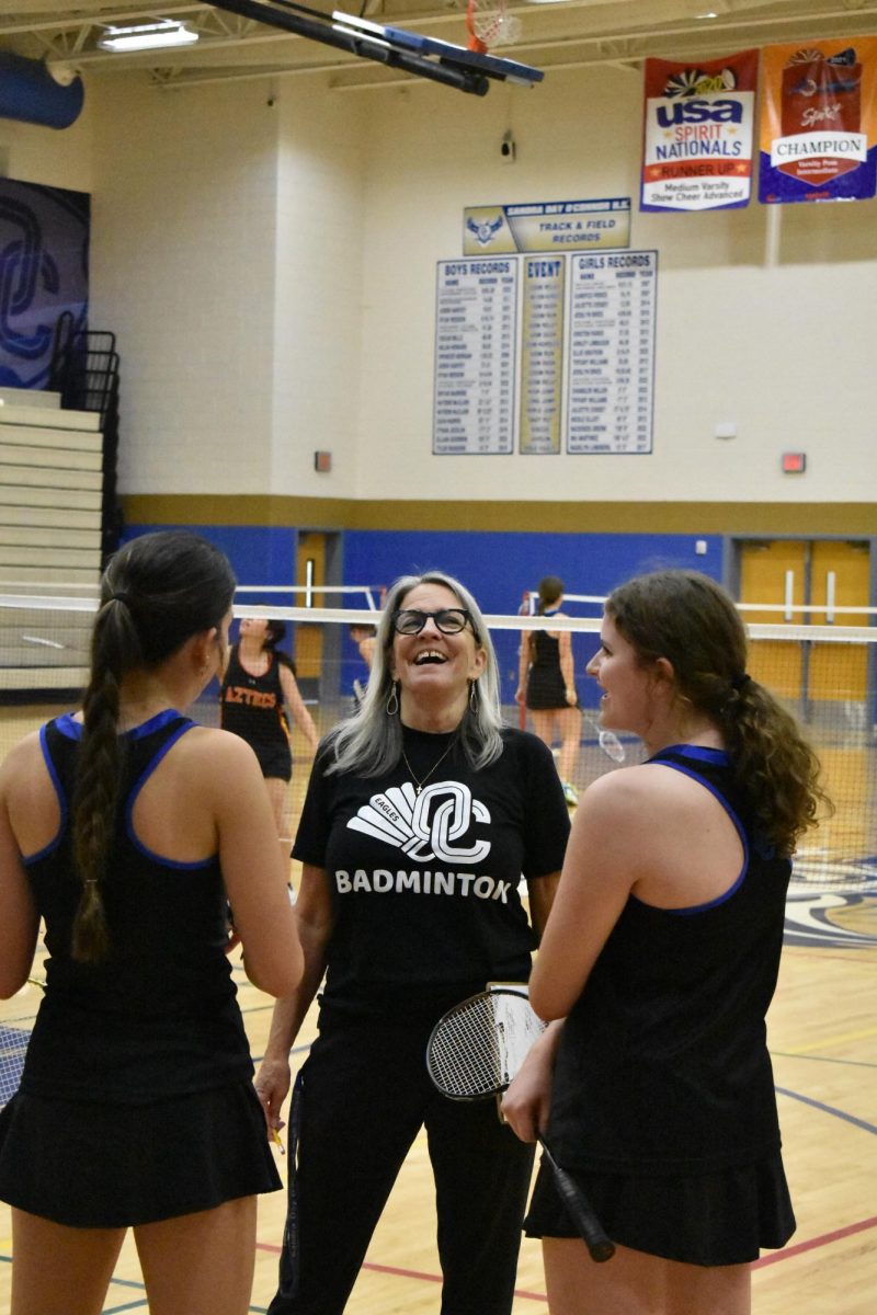 Coach Paula Cappelletti (center) laughs with Brynlee Evanson, junior (left), and Aubrey Baker, freshman (right), between games.