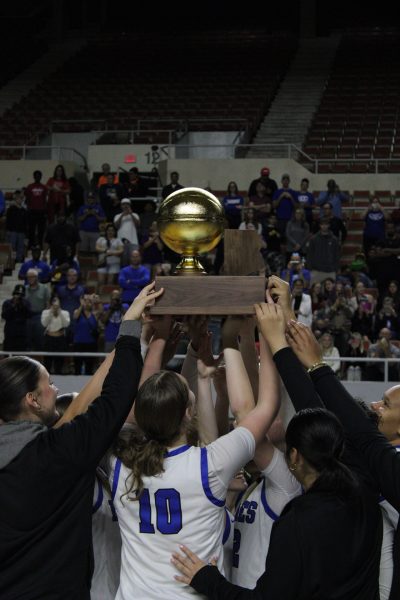 The girls basketball team hoists the trophy high after beating the Perry Pumas to win the state championship
