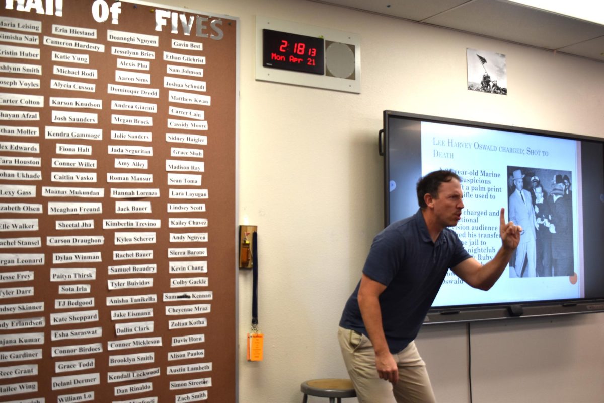 Uriah Cross, history teacher, gives a lecture next to his Wall of Fives.