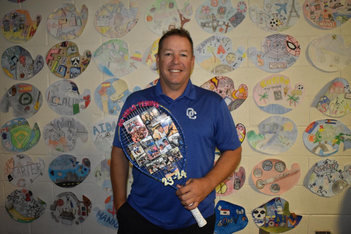 Art teacher Lance Gephart holding a customized tennis racket that his athletes made for him.